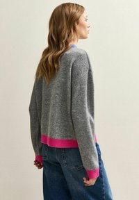 Grijze wollen trui met een cropped ontwerp, voorzien van felroze geribde manchetten en zoom. Ontspannen pasvorm met verlaagde schouders, gladde textuur.