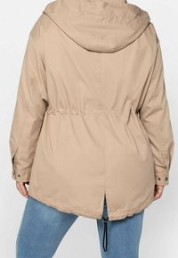 Beige Kapuzenjacke mit tailliertem Schnitt, verstellbarem Kordelzug und Druckknöpfen. Sie hat einen geraden Schnitt und ist aus leichtem Material.