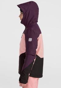 Veste colorée avec une capuche violette, un haut rose et une partie inférieure noire. Comprend une poche zippée et un écusson logo sur la manche.