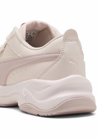 Sneaker Puma di un rosa pallido con tomaia in pelle liscia, suola imbottita e sottile logo accentuato sul tallone per un dettaglio aggiuntivo.