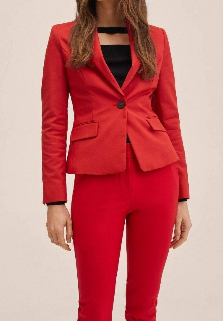 Blazer rouge à coupe ajustée, bouton noir unique, et deux poches avant, associé à un pantalon rouge sur mesure. Texture de tissu lisse.