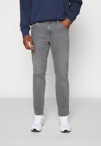 Grijze denim jeans met een rechte pasvorm, vijf-pocket ontwerp en subtiele vervaging, gecombineerd met witte sportschoenen.