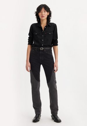 Sort denimskjorte med knaplukning og to brystlommer. Højtaljede jeans i sort og grå med kontrastpaneler. Sorte ankelstøvler.