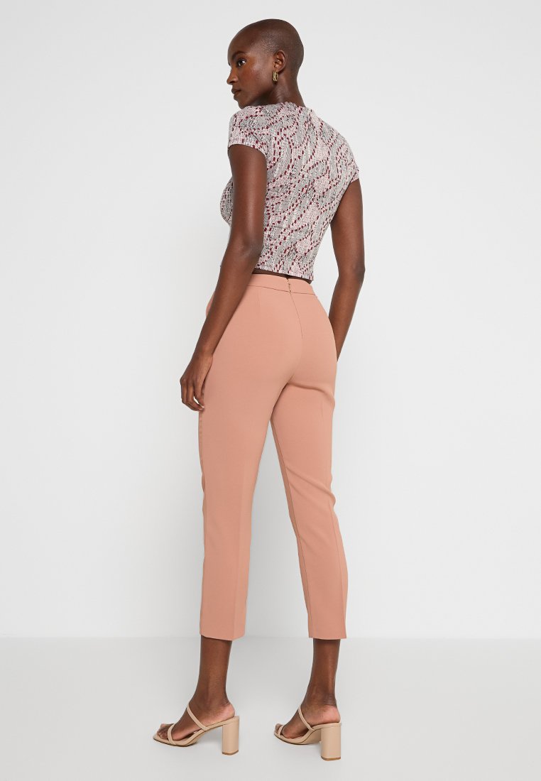 Krótkie wzorzyste topy w białym i czerwonym kolorze, zestawione z różowymi spodniami w slim fit. Ubranie charakteryzuje się krótkimi rękawami i subtelnymi detalami tekstury.