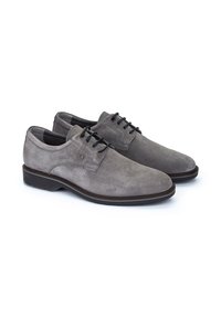 Chaussures en daim gris à lacets avec une texture lisse, bout rond et semelle foncée contrastante. Présente des œillets et des lacets noirs pour la fermeture.