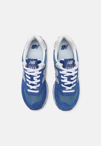 Blå mockaskinn och mesh sneakers med vita snören, med en silverfärgad "N"-logotyp, vadderad krage och märkestagg på tungan.