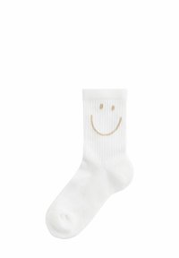 Weiße Baumwollknöchelsocke mit geripptem Muster, versehen mit einem goldenen Smiley-Gesicht auf der Vorderseite. Kompakte Form, weicher Stoff.