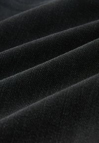 Melns audums ar mīkstu, teksturētu virsmu, kurā ir smalkas rievas un krokas, radot dimensiju bagātu izskatu.