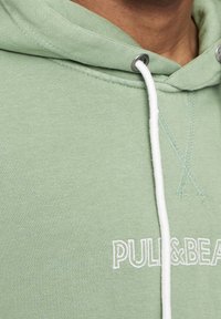 Felpa verde realizzata in tessuto misto cotone; presenta una tasca a marsupio, un laccio bianco e un logo del marchio ricamato in bianco.