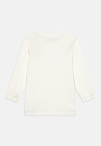 Camicia bianca in cotone a maniche lunghe con collo rotondo, caratterizzata da una trama morbida e un design semplice. Include un piccolo etichetta sul retro.