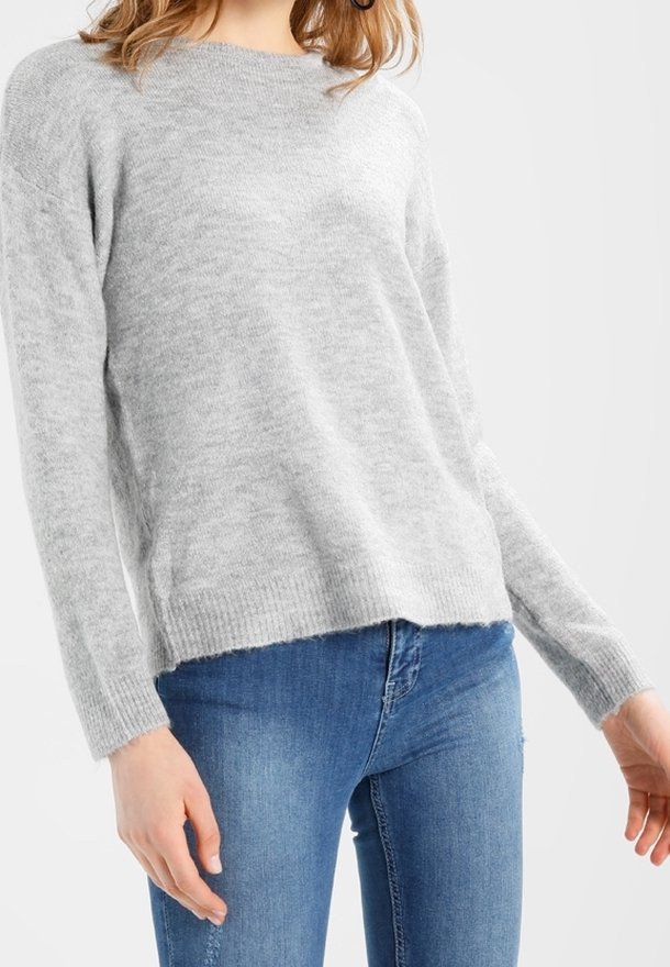 Pull gris clair en matière tricotée douce, à manches longues et coupe décontractée, associé à un jean en denim bleu.