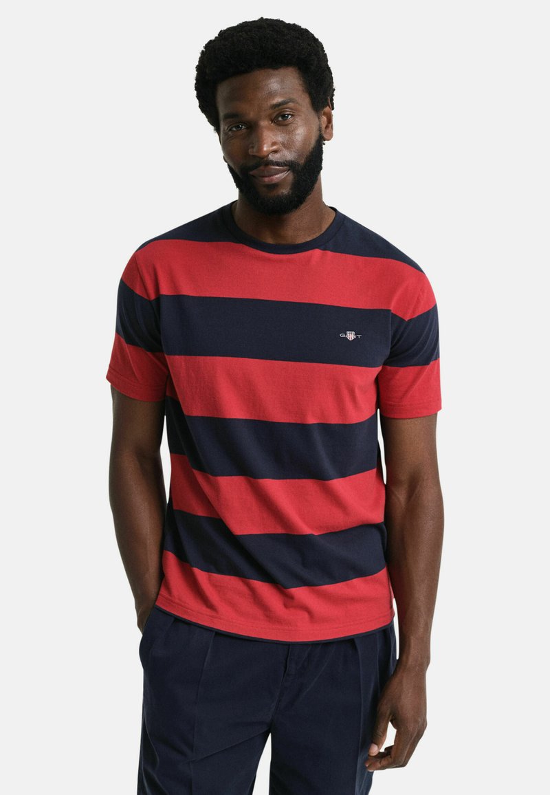 Rot und marineblau gestreiftes T-Shirt aus Baumwolle mit Rundhalsausschnitt und kurzen Ärmeln. Kleines Logo-Detail auf der Brust.