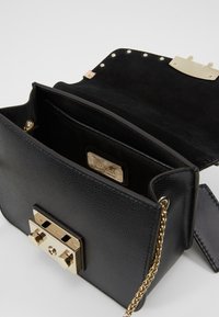 Borsa a tracolla in pelle nera con finitura strutturata, accessori color oro e tracolla a catena. L'interno presenta una fodera in suede e una targhetta del marchio.