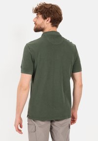 Donkergroen polo shirt met korte mouwen, gemaakt van zachte katoen, met een kraag en zijsplitten aan de zoom.