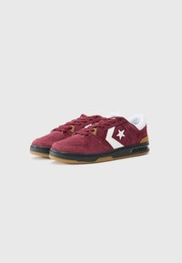 Burgundy suede sneakers with white star logo, round toe, black sole, and textured accents. Features white tongue and rounded laces.