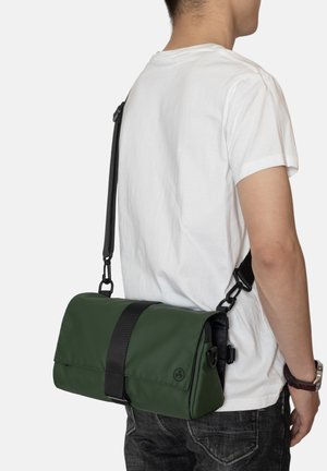 Borsa a messenger rettangolare verde con accenti neri, realizzata in tessuto liscio, dotata di una tracolla regolabile e di una chiusura a patta.