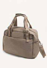 Borsa a tracolla beige imbottita con manici doppi, tracolla regolabile, tasca frontale e scomparti laterali su uno sfondo neutro.