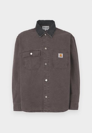 Camisa de manga larga en algodón gris oscuro con cuello de mezclilla negra. Cuenta con dos bolsillos en el pecho y botones a presión plateados. Logotipo de Carhartt en el bolsillo.