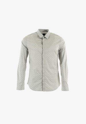 Chemise à manches longues de couleur gris clair avec un col boutonné, présentant un motif à pois et une texture subtile ; fermeture à boutons à l'avant.