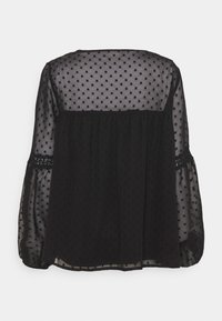Svart genomskinlig blus med polka prickar, elastisk midja och spetsdetaljer på ärmarna. Har en avslappnad passform och luftiga ärmar.