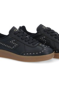 Baskets en cuir noir avec semelle en caoutchouc, présentant un design perforé orné, des lacets texturés et des bords déchiquetés sur la languette.