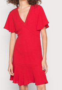 Vestido rojo con mangas cortas y ligeras, escote en V profundo, corsé ajustado, dobladillo acampanado y textura de tela suave.