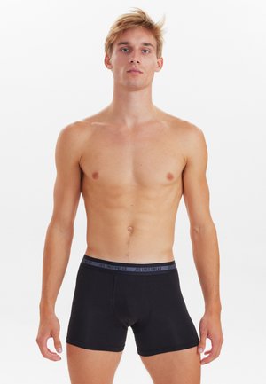 Schwarze Boxershorts aus Baumwolle mit einem elastischen grauen Bund, der mit "JBS UNDERWEAR" beschriftet ist. Glatte Textur und enganliegendes Design. Das Modell steht vor einem weißen Hintergrund.