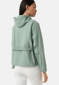 Lichtgroene, waterdichte jas met een capuchon, elastische tailleband en lange mouwen, met een ontspannen, cropped ontwerp.