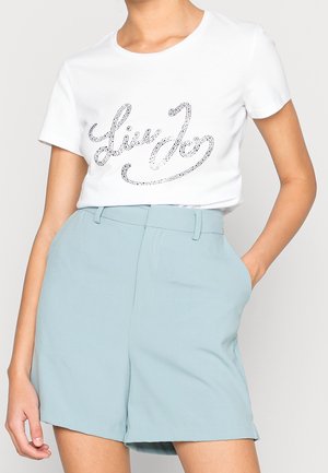 Witte T-shirt met korte mouwen en een ronde hals met zilveren rhinestone-schrift. Gecombineerd met lichtblauwe shorts met hoge taille en zijzakken.