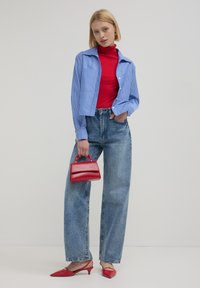 Camicetta cropped a righe blu e bianche, dolcevita rosso, jeans blu a vita alta, borsa rossa e scarpe rosse con punta.