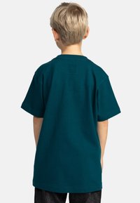 Turkis bomulds t-shirt med korte ærmer, rund hals og en afslappet pasform. Ensfarvet bagside uden synlige logoer eller mønstre.