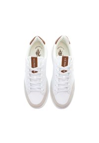 Bílé tenisky s hladkým koženým svrškem, světlými béžovými akcenty, hnědými patními taby a bílými tkaničkami. Na jazyku se nachází logo.