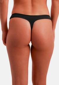 Black thong bikini bottom with minimal coverage, featuring smooth fabric, a low-rise waistband, and a clean finish along the edges.