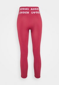 Leggings de sport rouges avec une taille épaisse arborant le texte "ADIDAS" en blanc. Texture lisse et design ajusté, se prolongeant jusqu'aux chevilles.