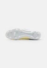 Nike soccer shoe sole, white with yellow accents, features circular traction studs and a textured surface for grip and stability.