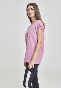 T-shirt rosa a maniche corte con una vestibilità comoda, abbinato a leggings neri con un dettaglio a striscia bianca. Tessuto morbido in cotone.