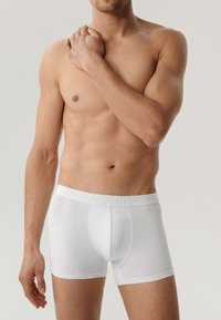 Białe bawełniane bokserki z teksturowanym paskiem w talii, na którym wypisano "ATLANTIC" w wytłaczanym stylu. Dopasowany krój, gładkie wykończenie i długość do połowy uda.