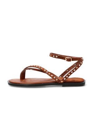 Sandalia plana marrón con tiras finas tachonadas, hebilla en el tobillo y suela negra, diseñada para uso casual.