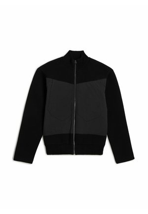 Giacca nera con zip, caratterizzata da un collo a maglia e una sezione frontale testurizzata con due taschini sul petto. Materiali a contrasto, vestibilità slim.