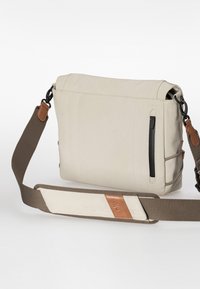 Beige Messenger Bag mit strukturiertem Design, ausgestattet mit einem abnehmbaren braunen Schulterriemen, einer seitlichen Reißverschlusstasche und Lederakzenten am Riemen.
