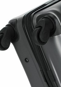 Schwarzer Hartschalenkoffer mit strukturiertem Oberflächendesign, ausgestattet mit einem glatten Reißverschluss und doppelten Drehrollen für einfache Mobilität.