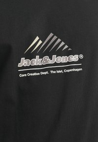 Sort bomulds t-shirt med et grafisk logo i hvid og grå. Inkluderer bjerge-design og tekst: "Jack & Jones, Core Creative Dept."