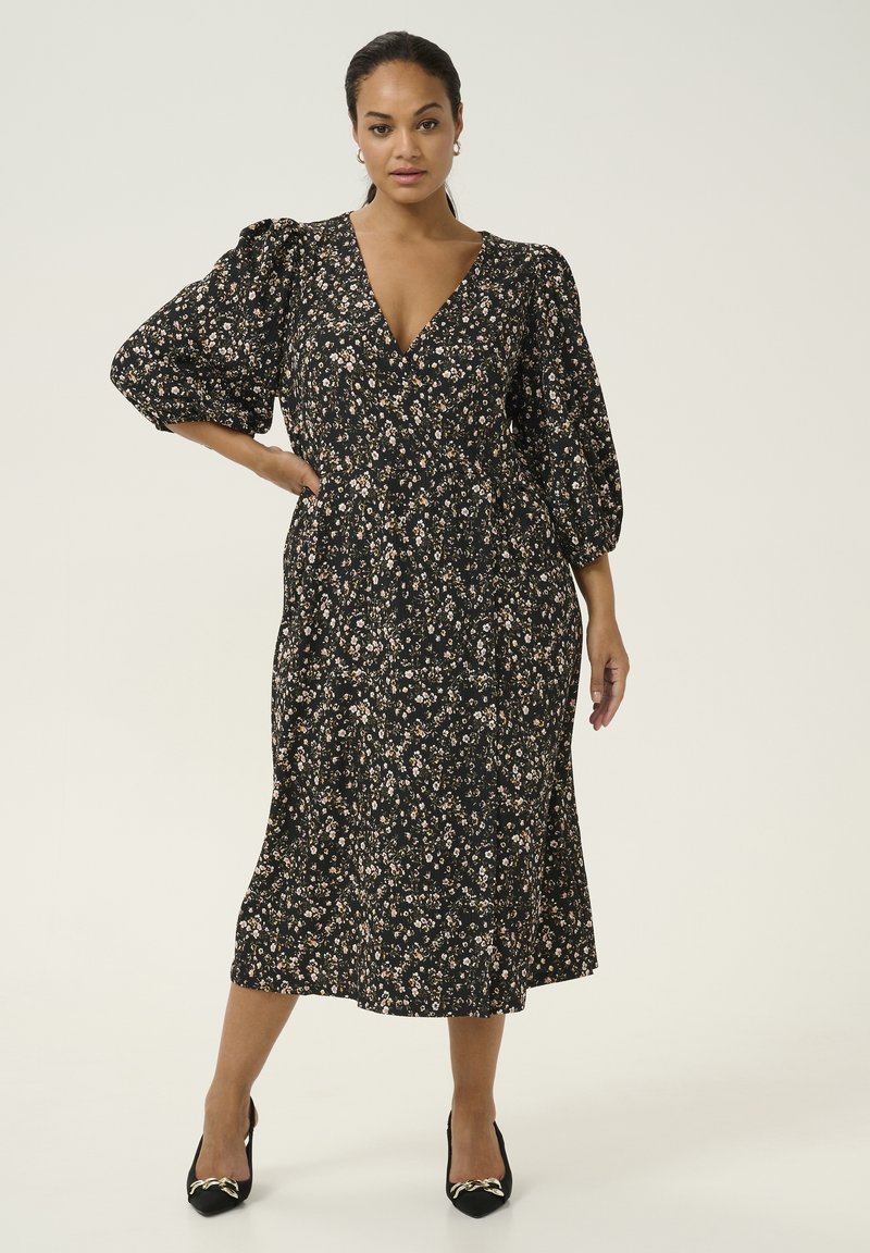 Black floral dress with a deep V-neckline and puffed sleeves, featuring a flowy mid-length skirt and a small, colorful floral pattern.