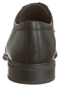 Chaussure en cuir noir à finition lisse, talon bas et détails cousus à l'arrière. Design ouvert avec une forme arrondie.
