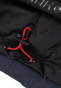 Tessuto nero con una superficie liscia presenta un cordino elastico regolabile di colore rosso. Include dettagli in hardware nero e cuciture.