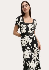 Czarna sukienka w kwiaty z krótkimi bufkami, kwadratowym dekoltem wykończonym koronką oraz białymi kwiatowymi wzorami. Miękka tkanina, zwiewny krój.