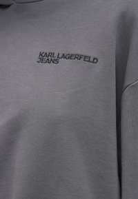 Γκρι φούτερ φτιαγμένο από μαλακό ύφασμα με στρογγυλή λαιμόκοψη και κεντημένο λογότυπο "KARL LAGERFELD JEANS" σε ταιριαστό χρώμα.