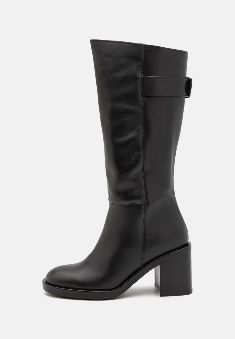 Botte montante en cuir noir avec un talon bloc, une finition lisse, un bout arrondi et un détail de sangle latérale.