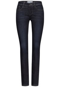 Jean skinny bleu foncé en denim, présentant un design standard à cinq poches, des accessoires en métal argenté et des coutures contrastantes.