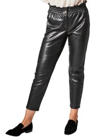 Pantalons en simili cuir noir avec une taille élastique, longueur cropped et texture brillante. Associés à des mocassins noirs pour le contraste.